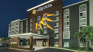 A hotel with a prominent 'La Quinta' sign, a large sun logo, and a distinctive geometric design on the facade. - La Quinta Inn & Suites by Wyndham San Antonio Downtown (San Antonio)