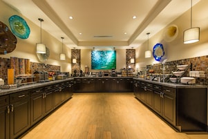 A spacious kitchen with dark cabinetry, a central island, and a large, colorful abstract painting on the wall.