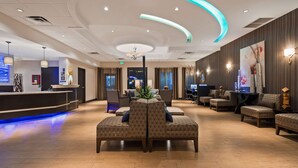 A hotel lobby with a reception desk, seating area, and a bar. - Best Western Plus Hollywood/Aventura (Hallandale Beach)