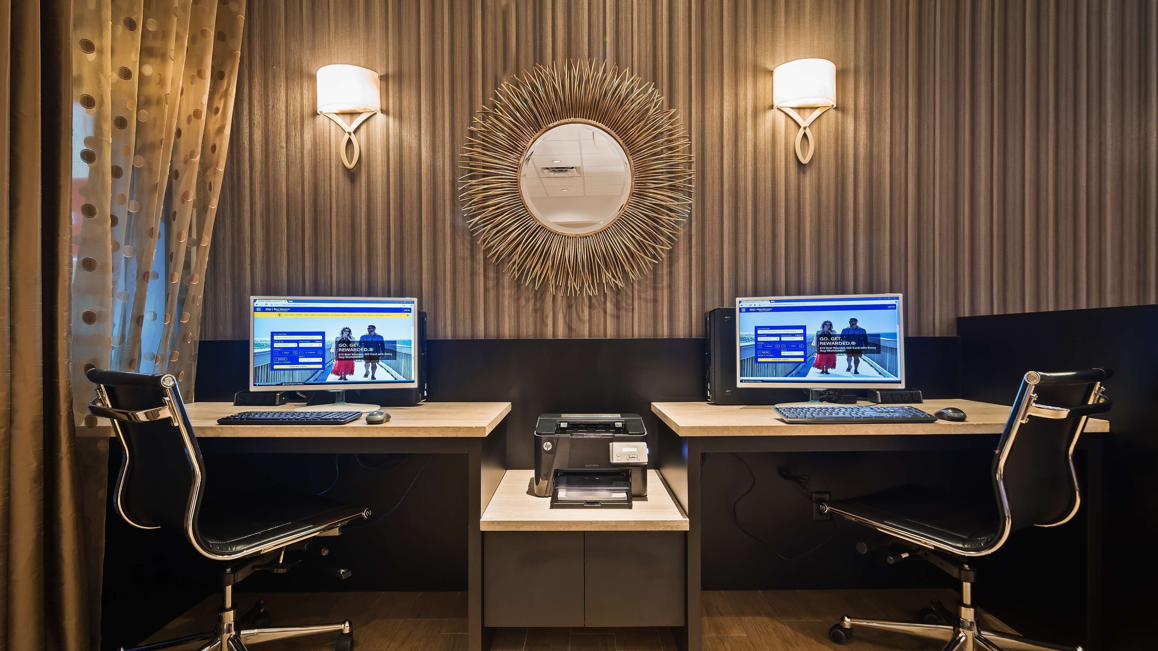 A modern office space with two desks, each with a computer, a printer, and a chair.