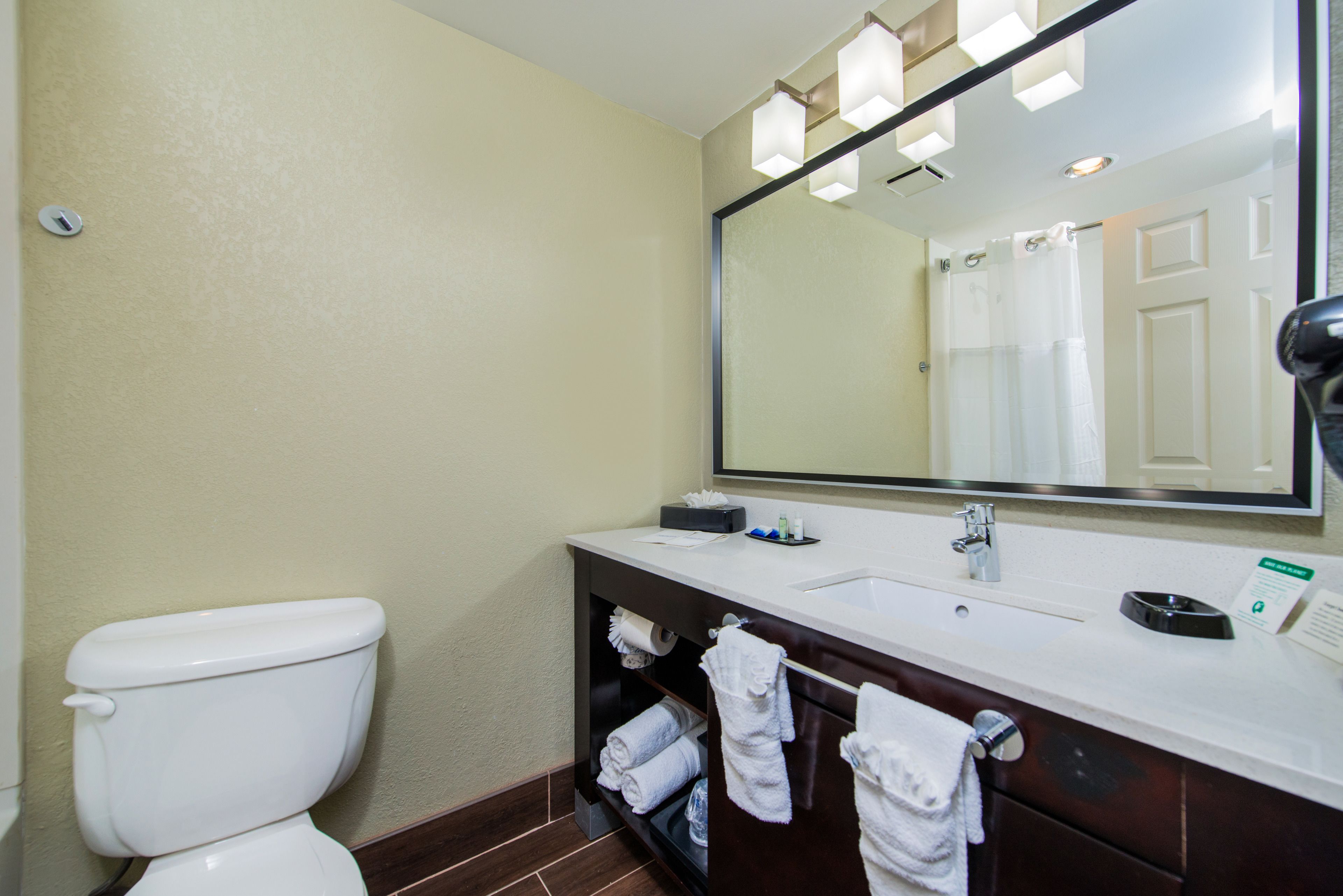 A bathroom with a toilet, sink, and mirror.