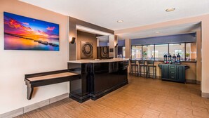A modern kitchen with a bar area, wooden flooring, and a large painting of a sunset.