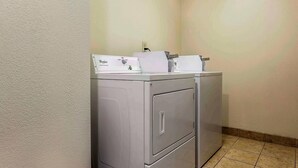 A laundry room with a front-loading washer and dryer, a wall-mounted electrical outlet, and a tiled floor. - Quality Inn & Suites Salisbury South (Salisbury)