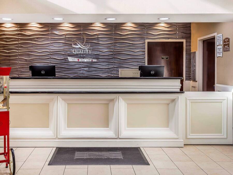 A reception desk with a modern design, a Dell computer, and a red cart.