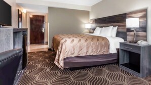 A hotel room with a bed, bedside lamps, a TV, and a desk.