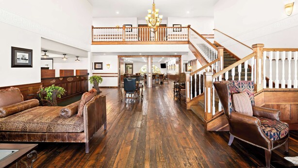 A spacious living area with a high ceiling, wooden flooring, a central staircase, and a chandelier. - Best Western Newberry Station (La Pine)