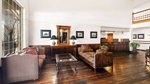 A spacious living area with a large window, a wooden reception desk, and a high ceiling. - Best Western Newberry Station (La Pine)