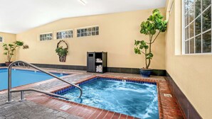 A swimming pool with a metal ladder, surrounded by potted plants, and a tiled edge. - Best Western Newberry Station (La Pine)