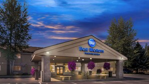 A Best Western hotel with a modern design, featuring a covered entrance, outdoor seating, and purple flowers. - Best Western Newberry Station (La Pine)