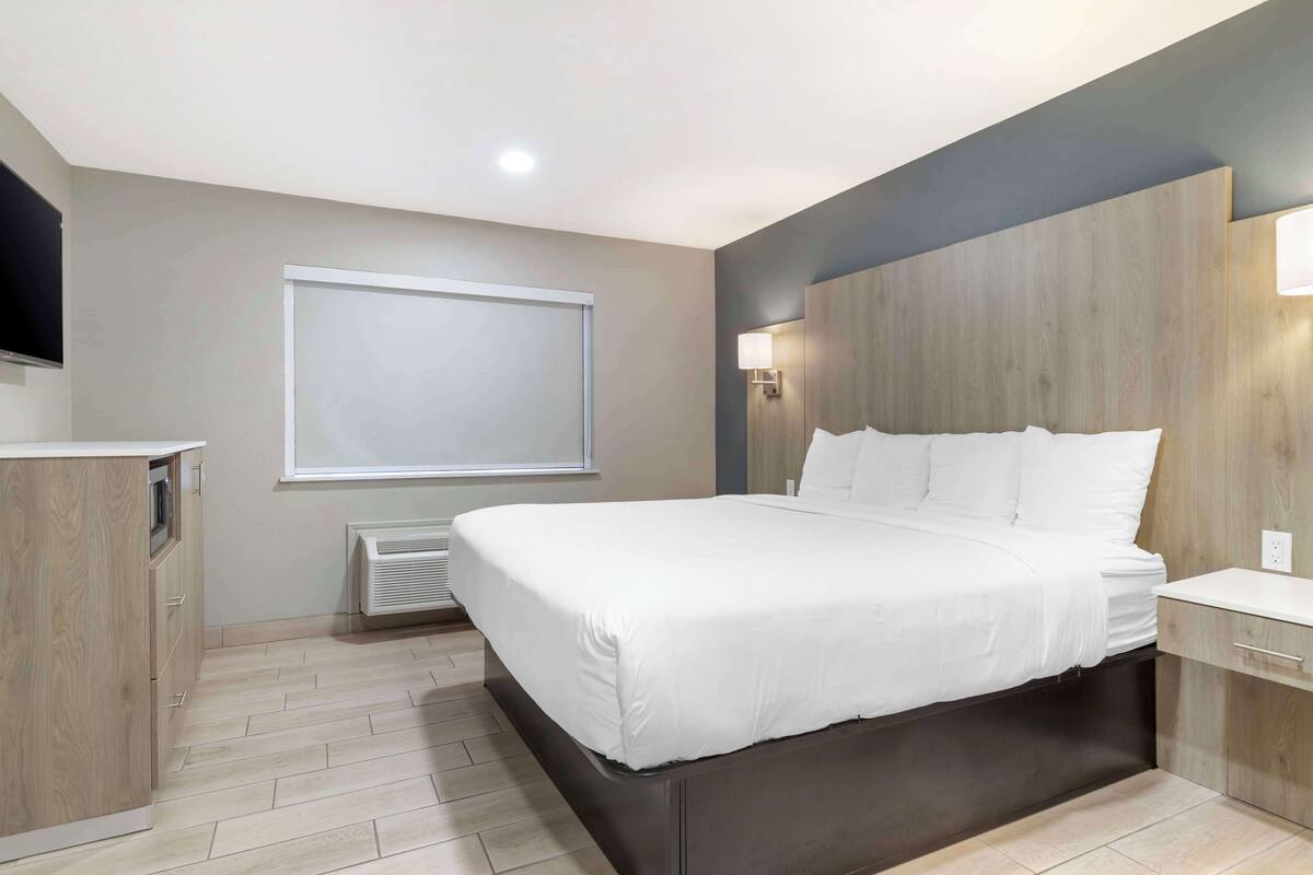 A modern hotel room with a large bed, built-in wardrobe, and a flat-screen TV.