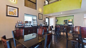 A modern restaurant with a high ceiling, wooden chairs, and a coffee machine. - Best Western Windsor Inn (Dumas)