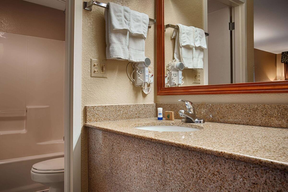 A bathroom with a granite countertop, a sink, a mirror, and a towel rack.