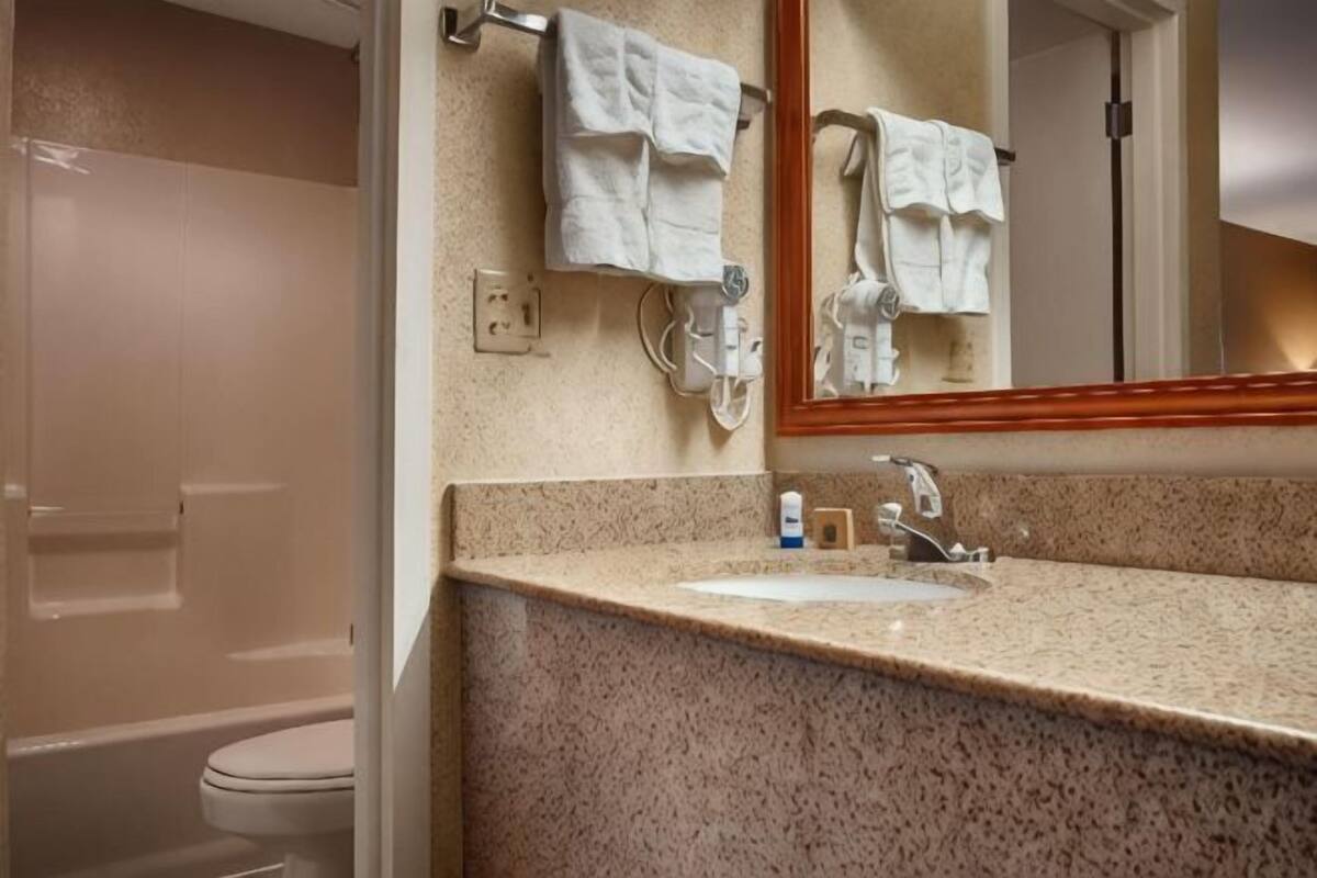 A bathroom with a sink, mirror, and towel rack.