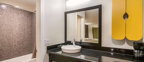 A bathroom with a white sink, black countertop, and a mirror.