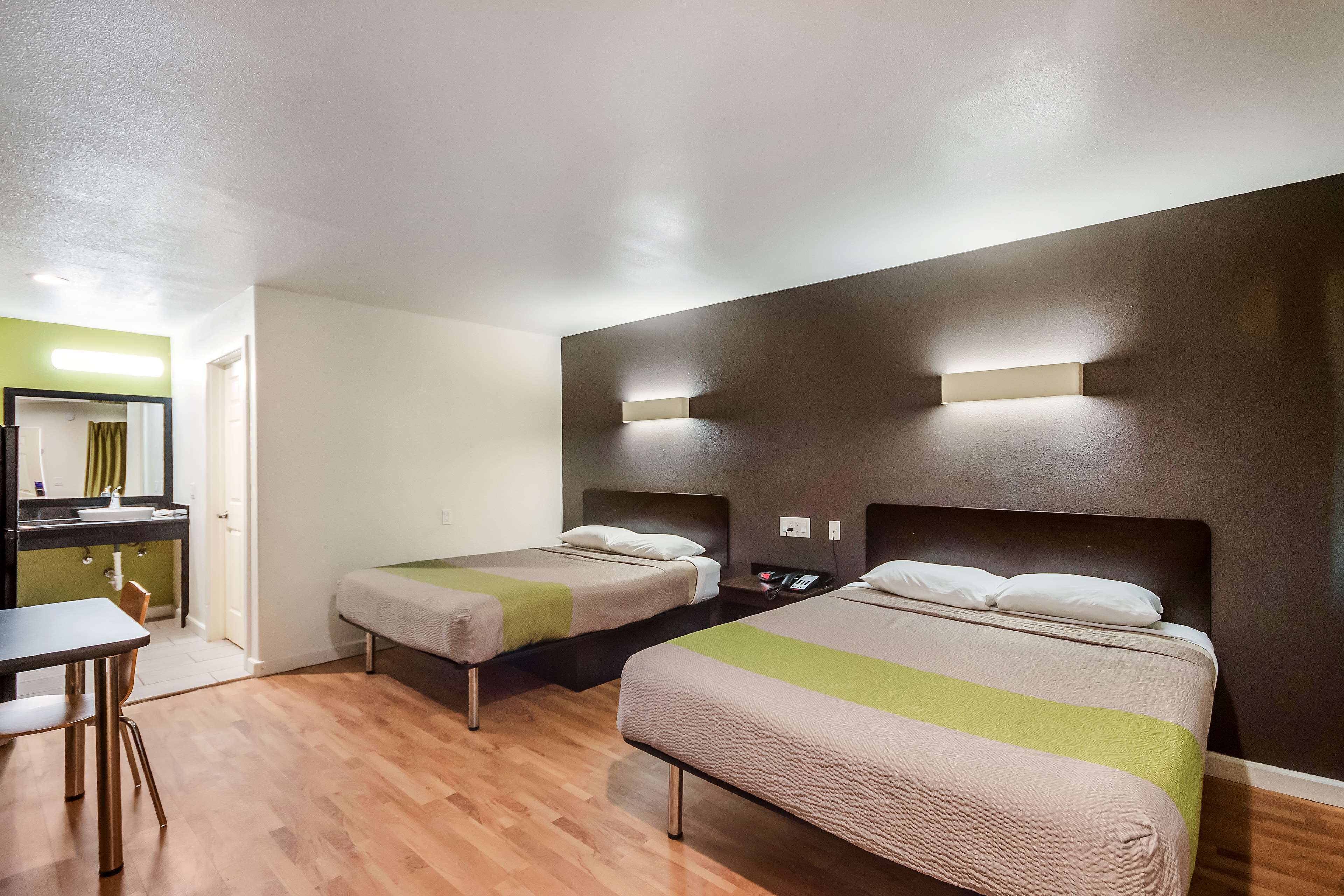Ein Hotelzimmer mit zwei Betten, einem Schreibtisch und einem Spiegel.