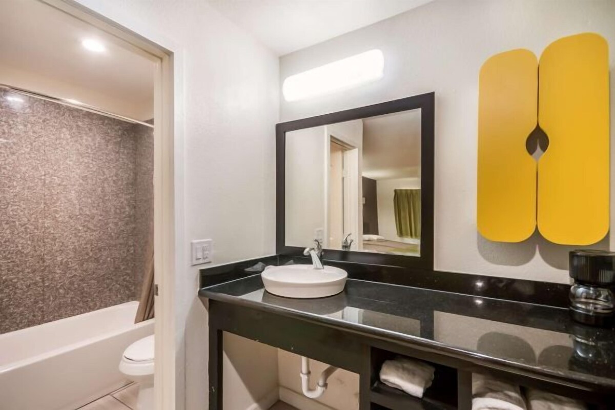 Une salle de bain moderne avec un plan de toilette noir, un lavabo blanc et un grand miroir.