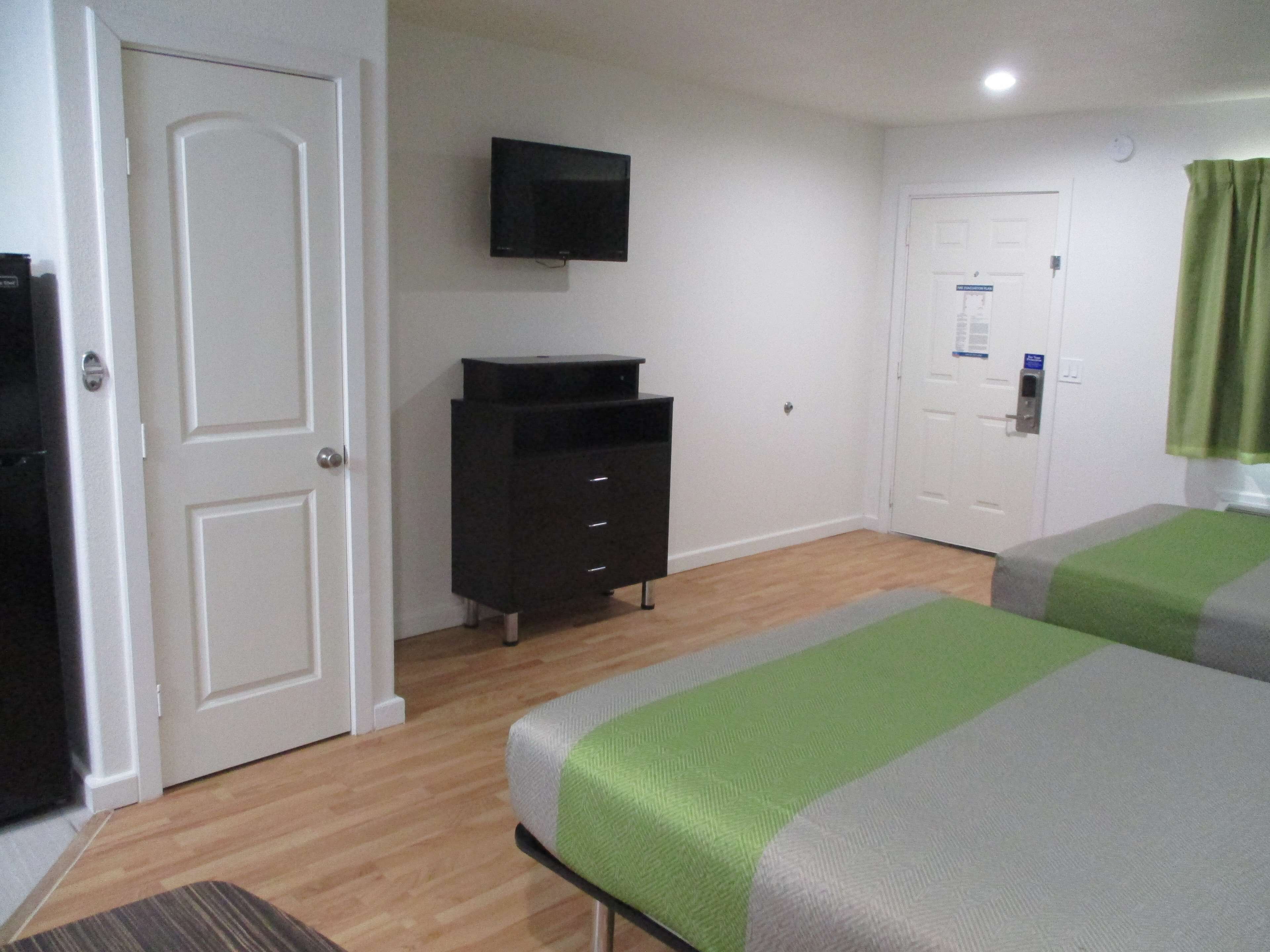 Une chambre d’hôtel avec un lit, une commode, une télévision et une porte.