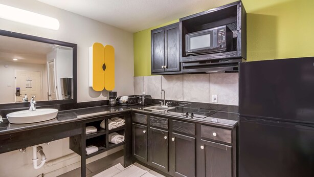 A modern kitchen with a black refrigerator, a microwave, and a sink. - Studio 6 Huntsville, TX (Huntsville)