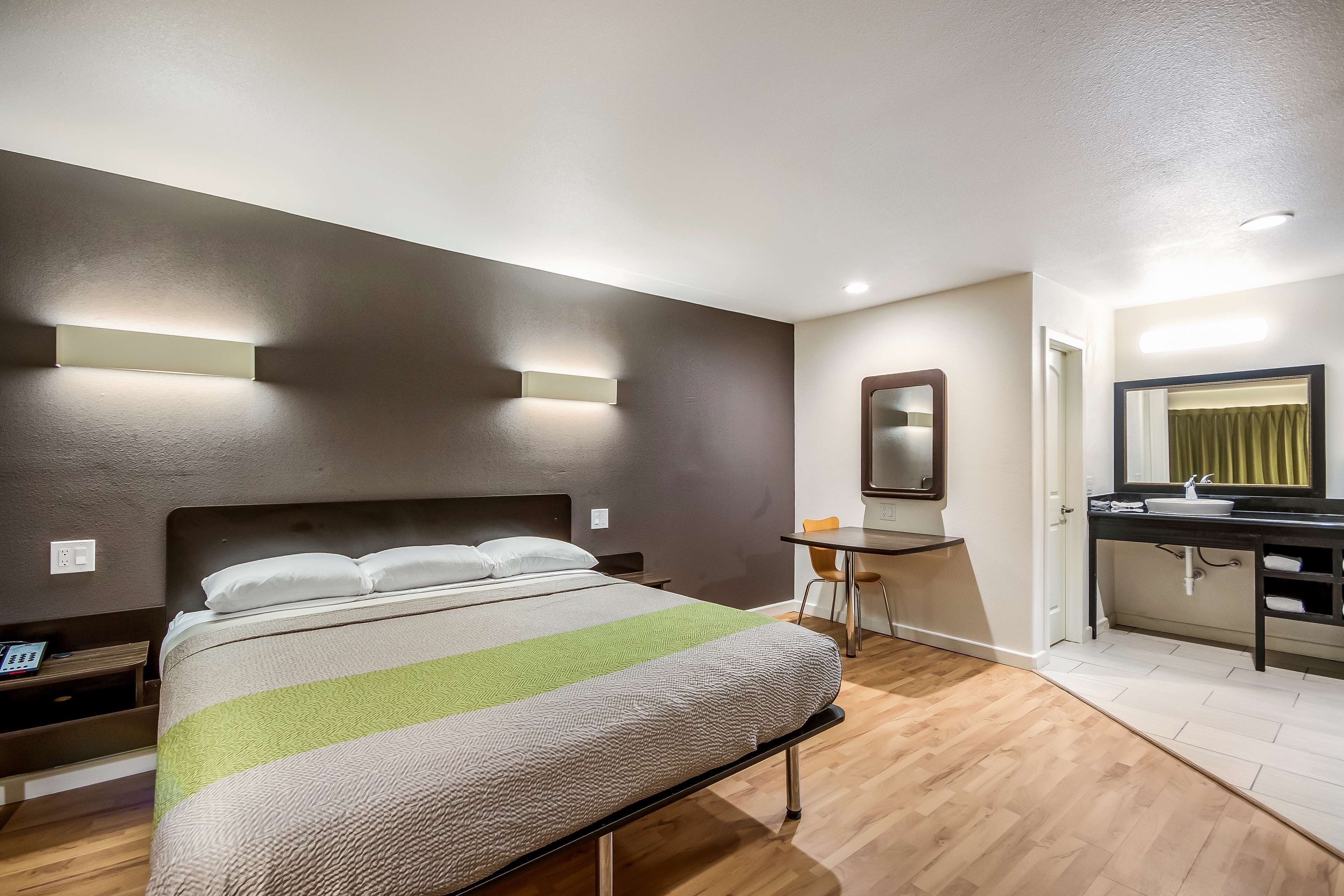 Una habitación de hotel moderna con una cama grande, una mesita de noche y un pequeño escritorio con una silla.