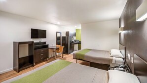 A hotel room with two beds, a desk, a chair, a TV, and a kitchenette. - Studio 6 Huntsville, TX (Huntsville)