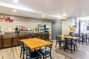 A restaurant with wooden tables and chairs, a coffee machine, and a refrigerator. - Quality Inn Buffalo (Buffalo)