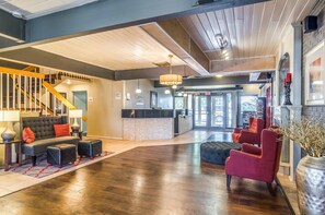 A spacious lobby with a reception desk, a staircase, and a seating area with a sofa and ottomans. - Quality Inn Buffalo (Buffalo)
