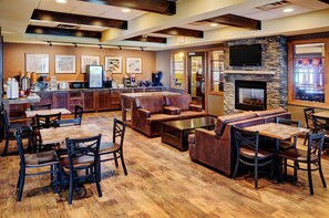 A restaurant with wooden flooring, leather seating, a bar area, and a fireplace.