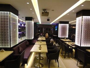 Een modern restaurant met zowel zitbankjes als tafels, met verlichte menukaarten en een eigentijds interieur.