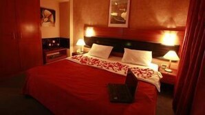 A hotel room with a large bed, two bedside lamps, a nightstand, and a wooden headboard. - Duroy Hotel (Beirut)