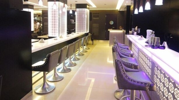 A modern bar area with a long counter, multiple bar stools, and pendant lighting. - Duroy Hotel (Beirut)