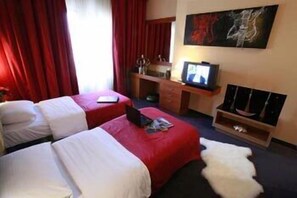 Een hotelkamer met twee bedden, een televisie, een bureau en een schilderij aan de muur.