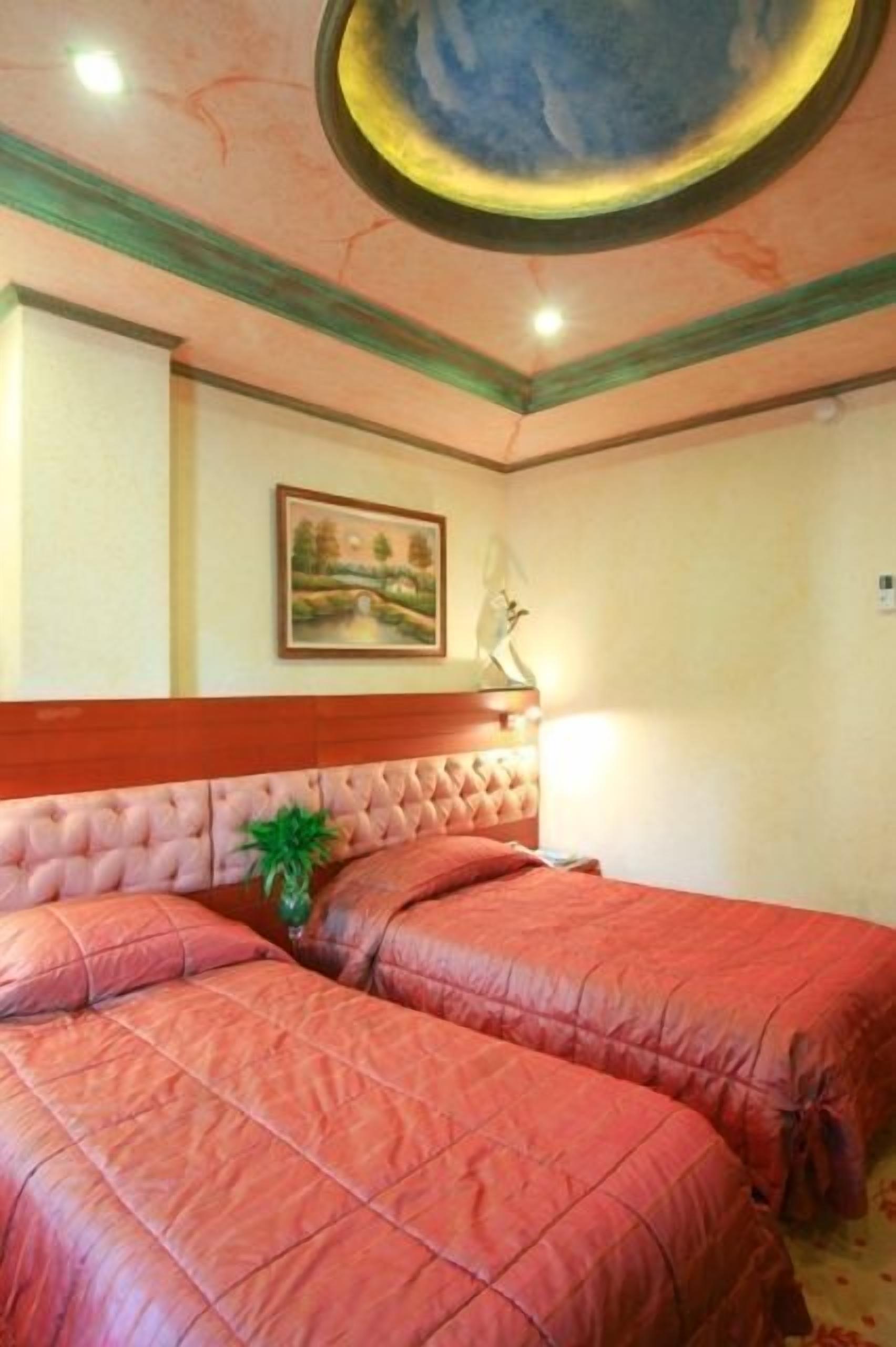 Een hotelkamer met twee bedden, een schilderij aan de muur en een plafond met een rond ontwerp.