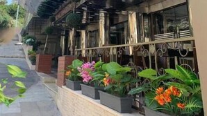 A modern hotel facade with a red flag, outdoor seating area, and potted plants. - Duroy Hotel (Beirut)