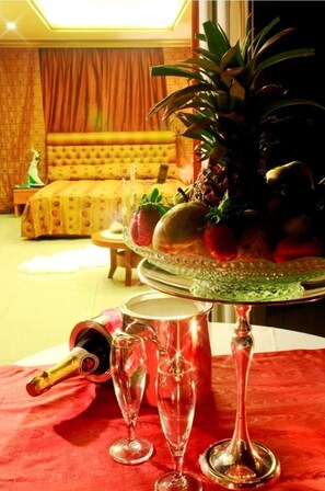 A room with a bed, a dining table with a fruit centerpiece, and a bottle of champagne. - Duroy Hotel (Beirut)