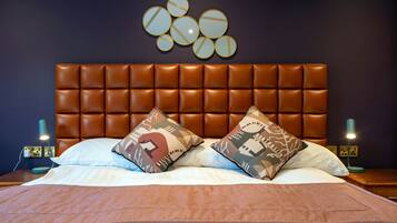 A neatly made bed with a brown headboard, two patterned pillows, and a brown throw blanket.