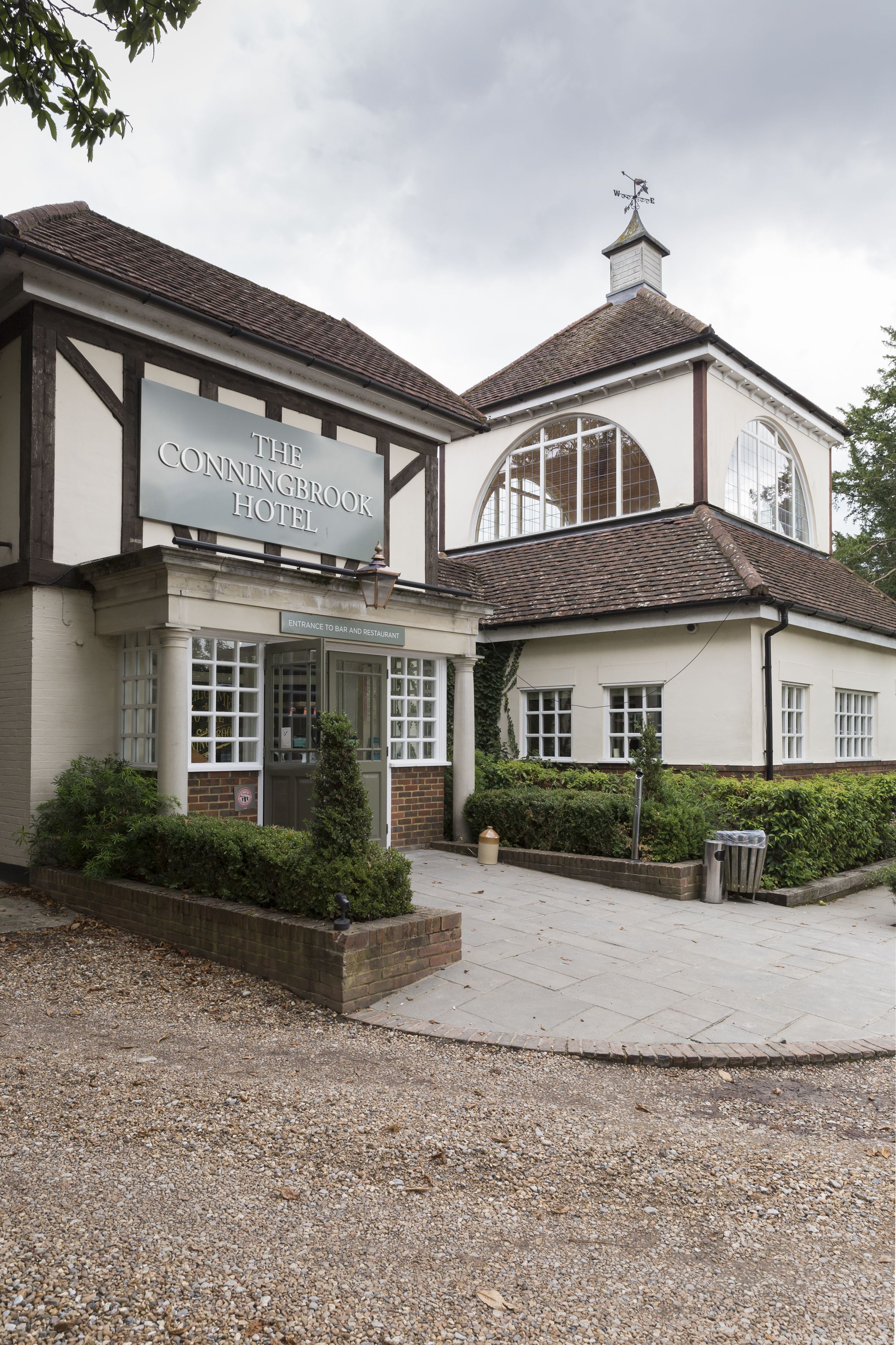 The Conningbrook Hotel with a traditional facade, large windows, and a gravel driveway.