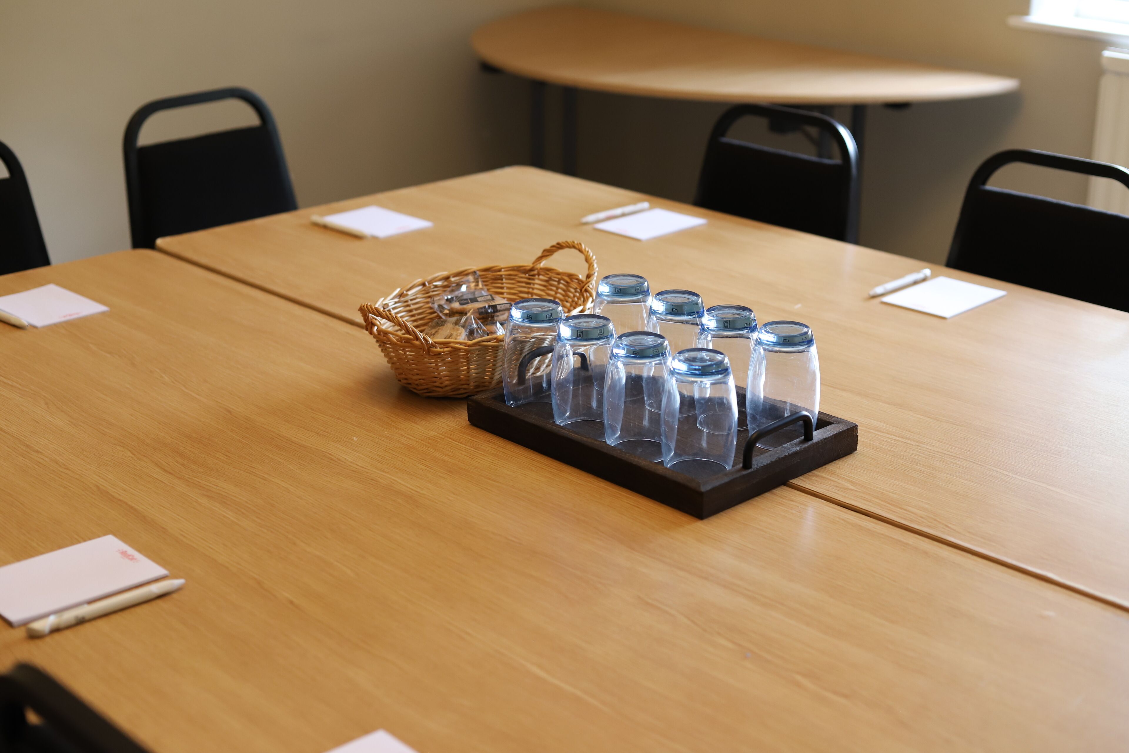 Una mesa de madera con un recipiente de vidrio transparente y una cesta de mimbre.