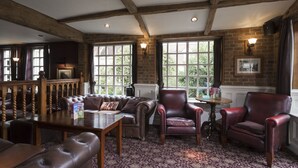 A cozy room with a wooden ceiling, leather furniture, and large windows with a view of greenery. - The Conningbrook Hotel (Ashford)