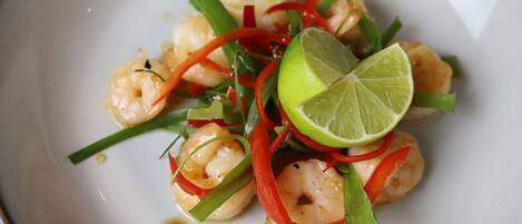 Un plato de camarones con adorno de lima y pimiento rojo.