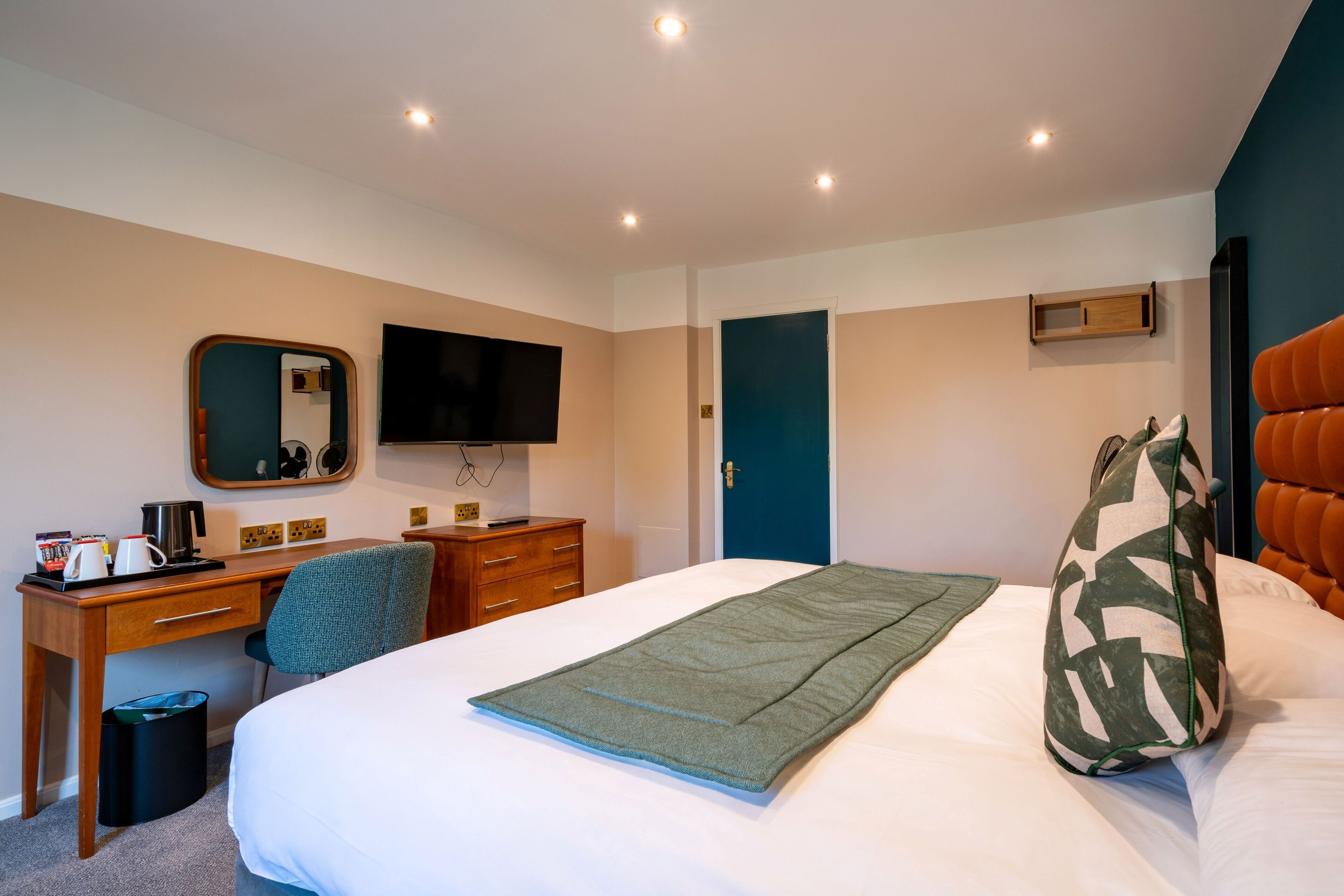 A hotel room with a bed, a desk, a chair, a television, and a wardrobe.
