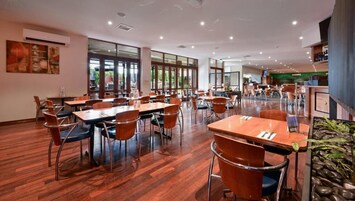 Uma ampla sala de jantar com várias mesas e cadeiras, janelas grandes e design de interiores moderno.