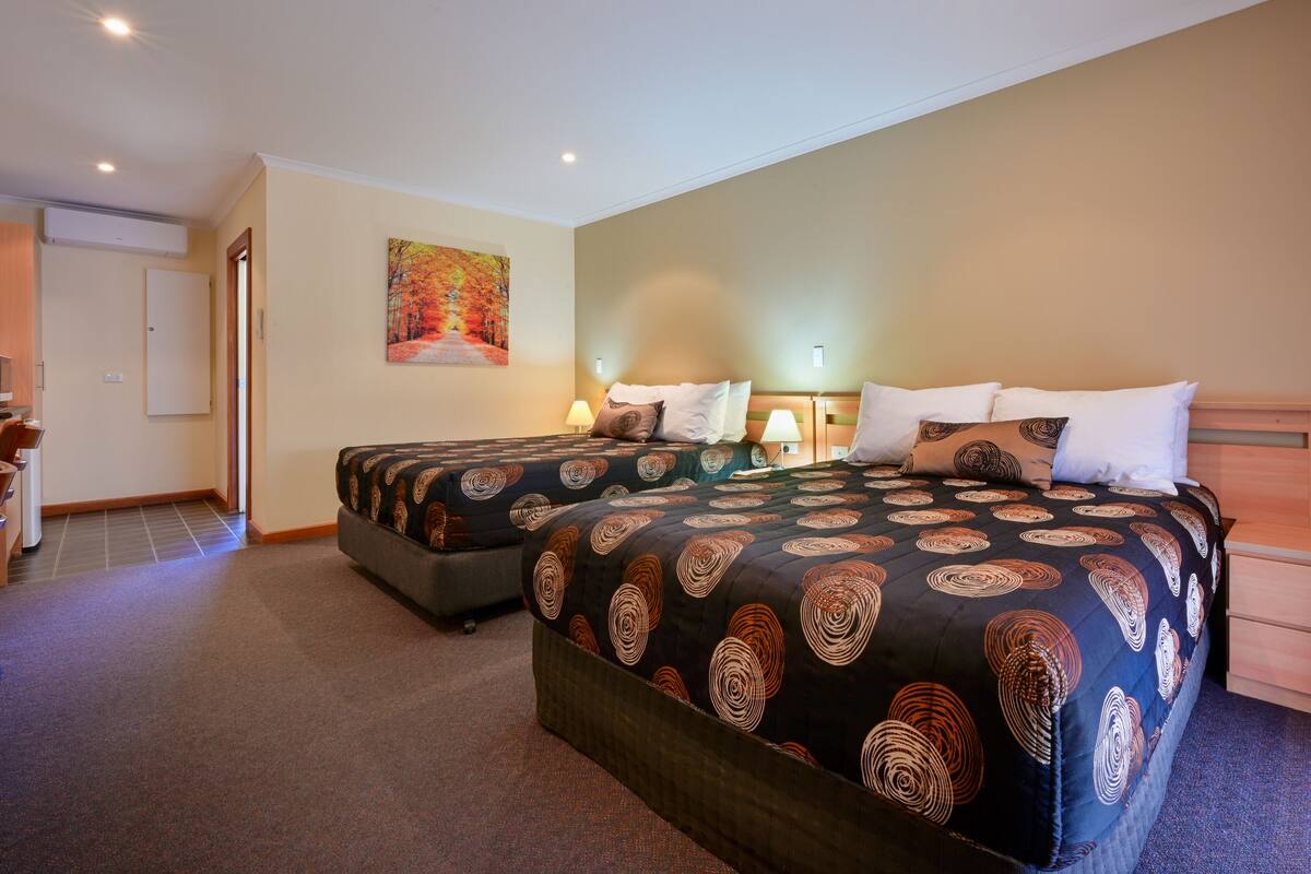 A double room with two beds, a desk, and a chair.