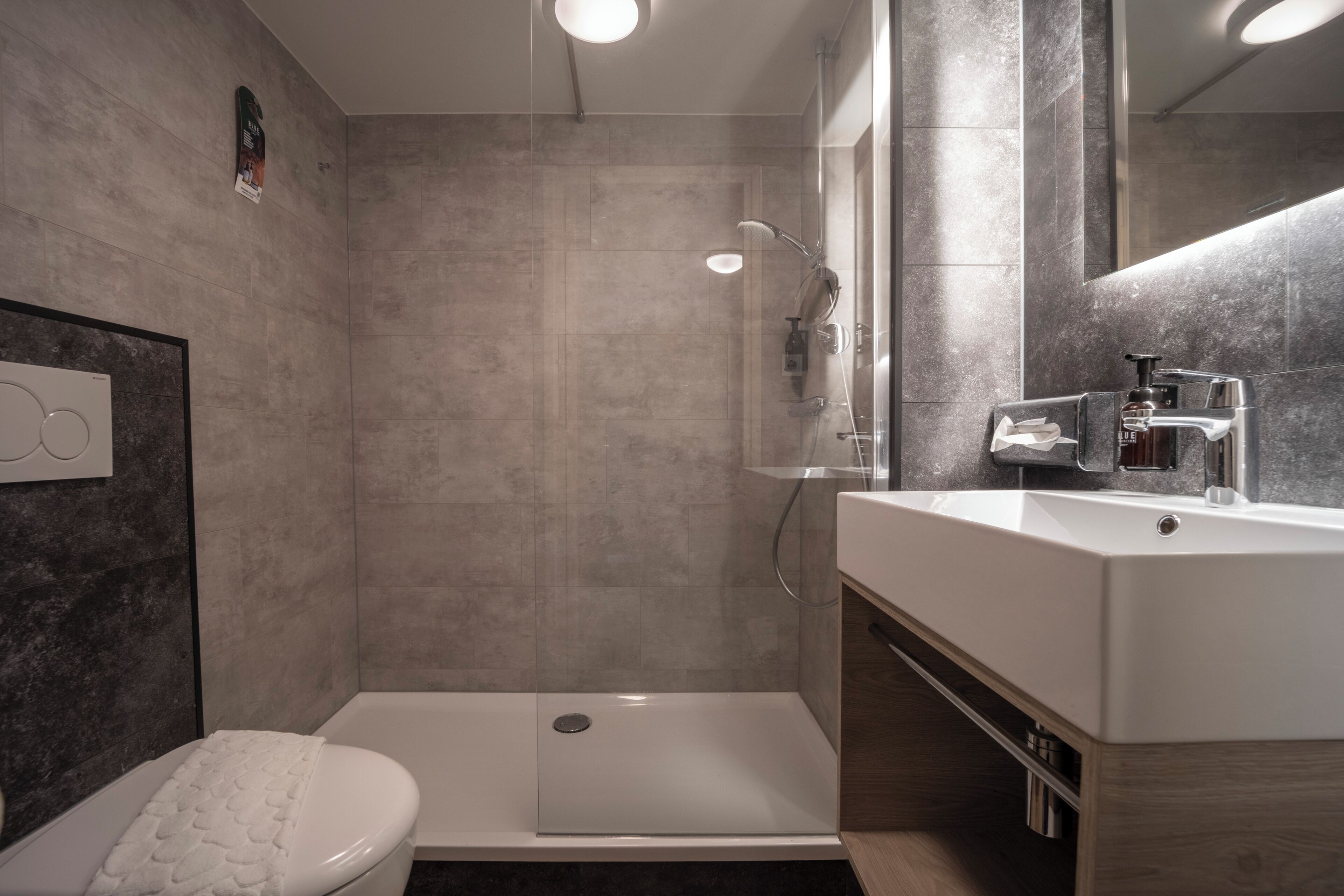 A modern bathroom with a shower, toilet, and sink.