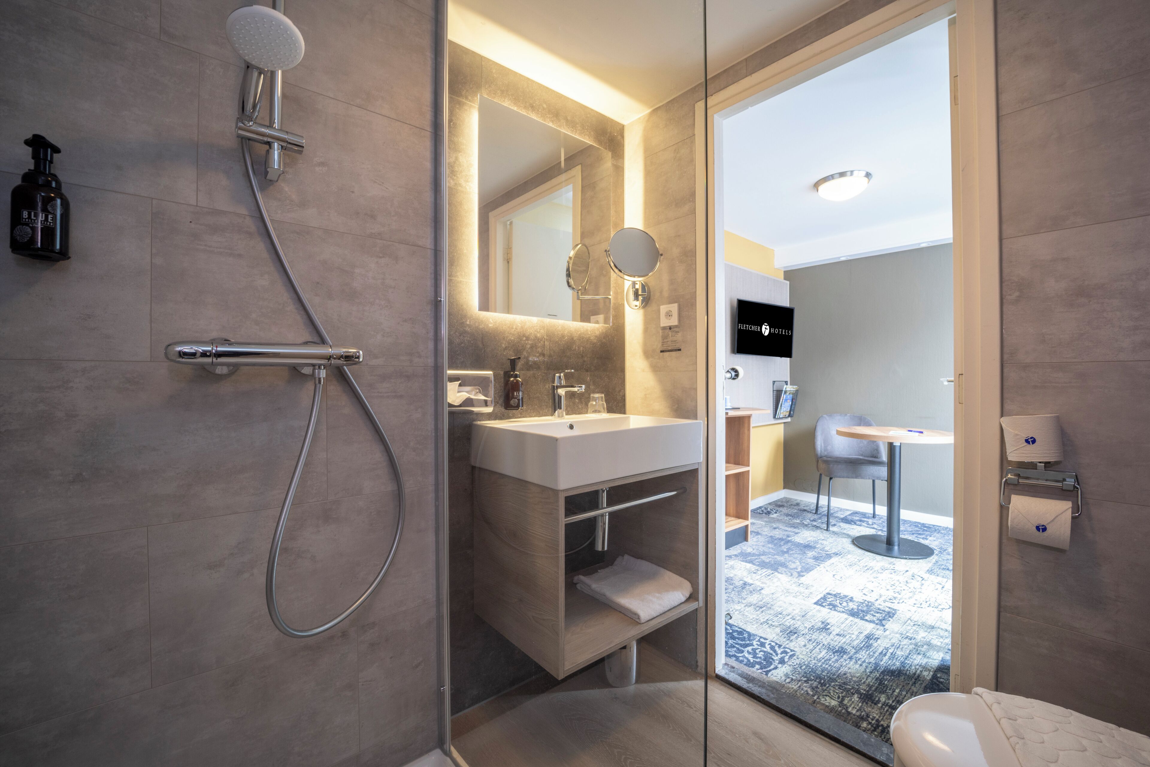 A modern bathroom with a glass-enclosed shower, a vanity with a mirror, and a toilet.