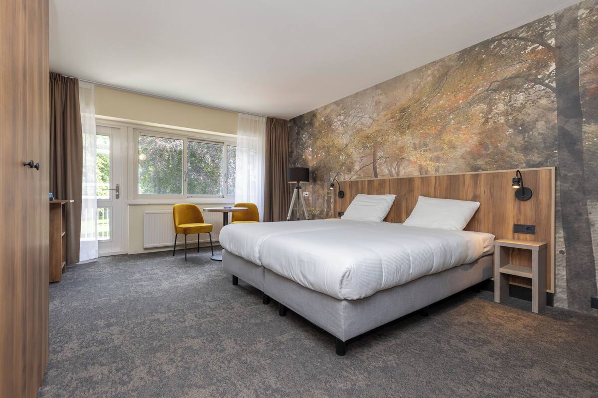 Moderni hotellihuone, jossa on suuri sänky, työpöytä ja tuoli.