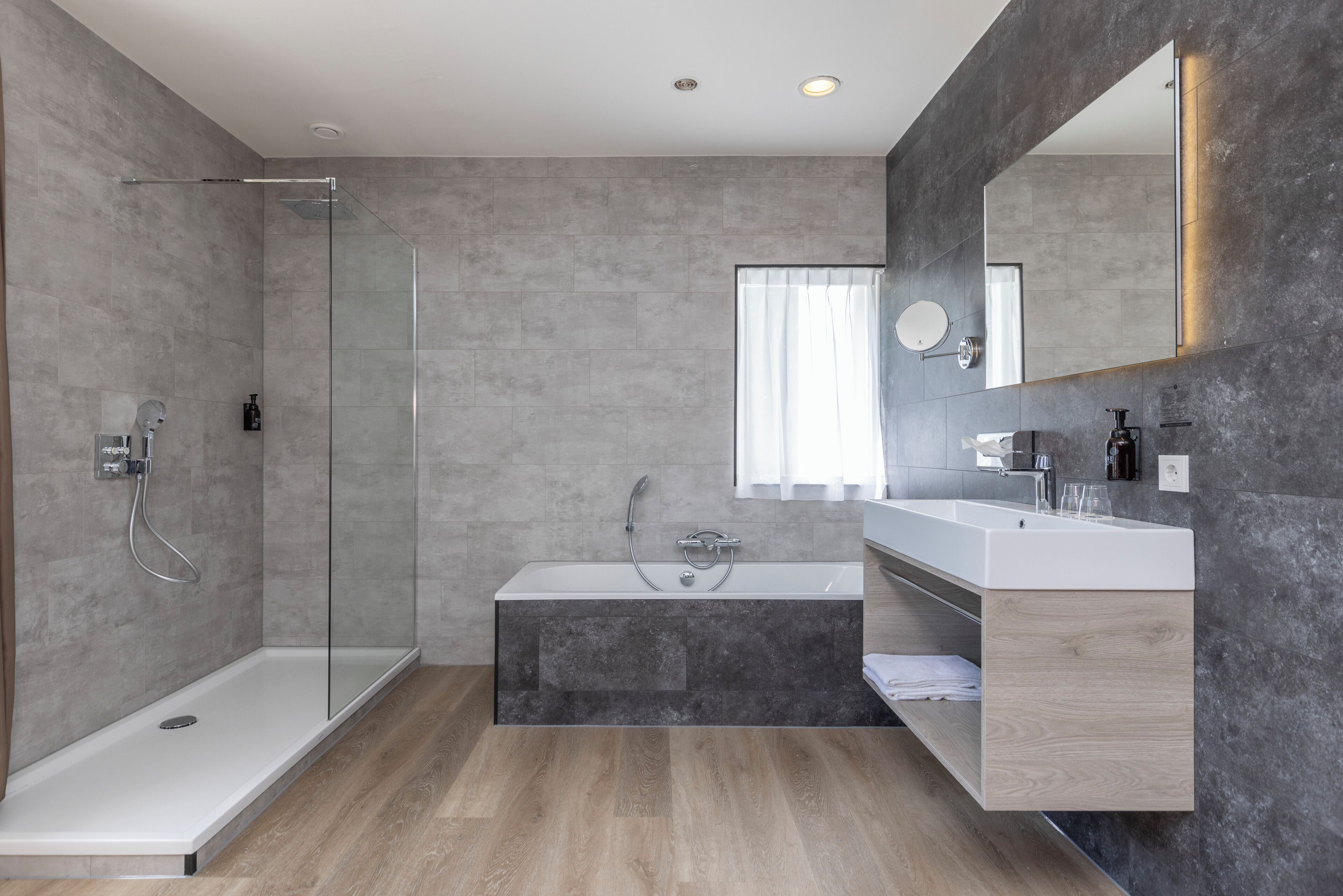 A modern bathroom with a glass-enclosed shower, a freestanding bathtub, and a vanity with a mirror.