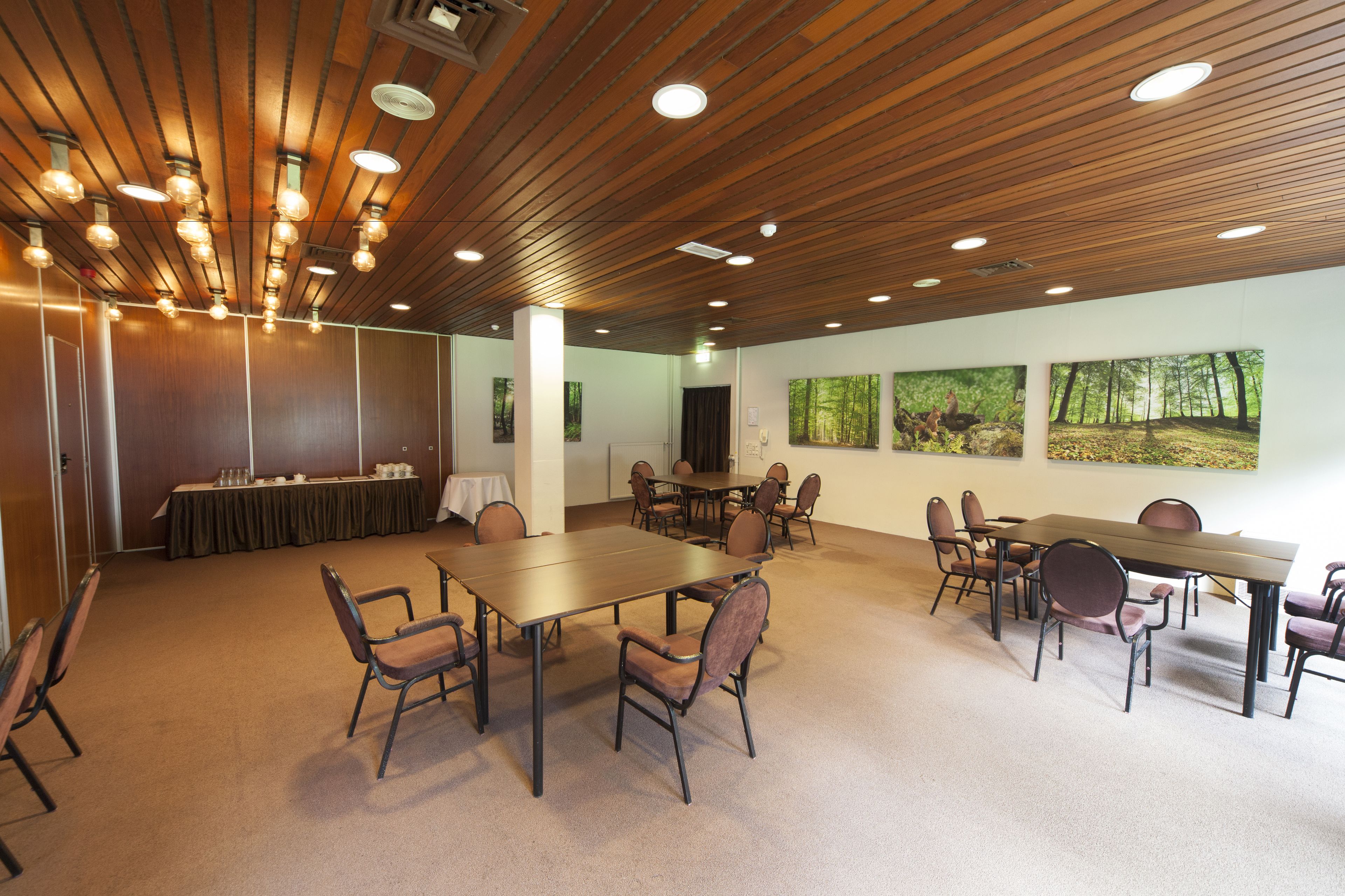 A conference room with wooden ceiling, multiple tables, and chairs.