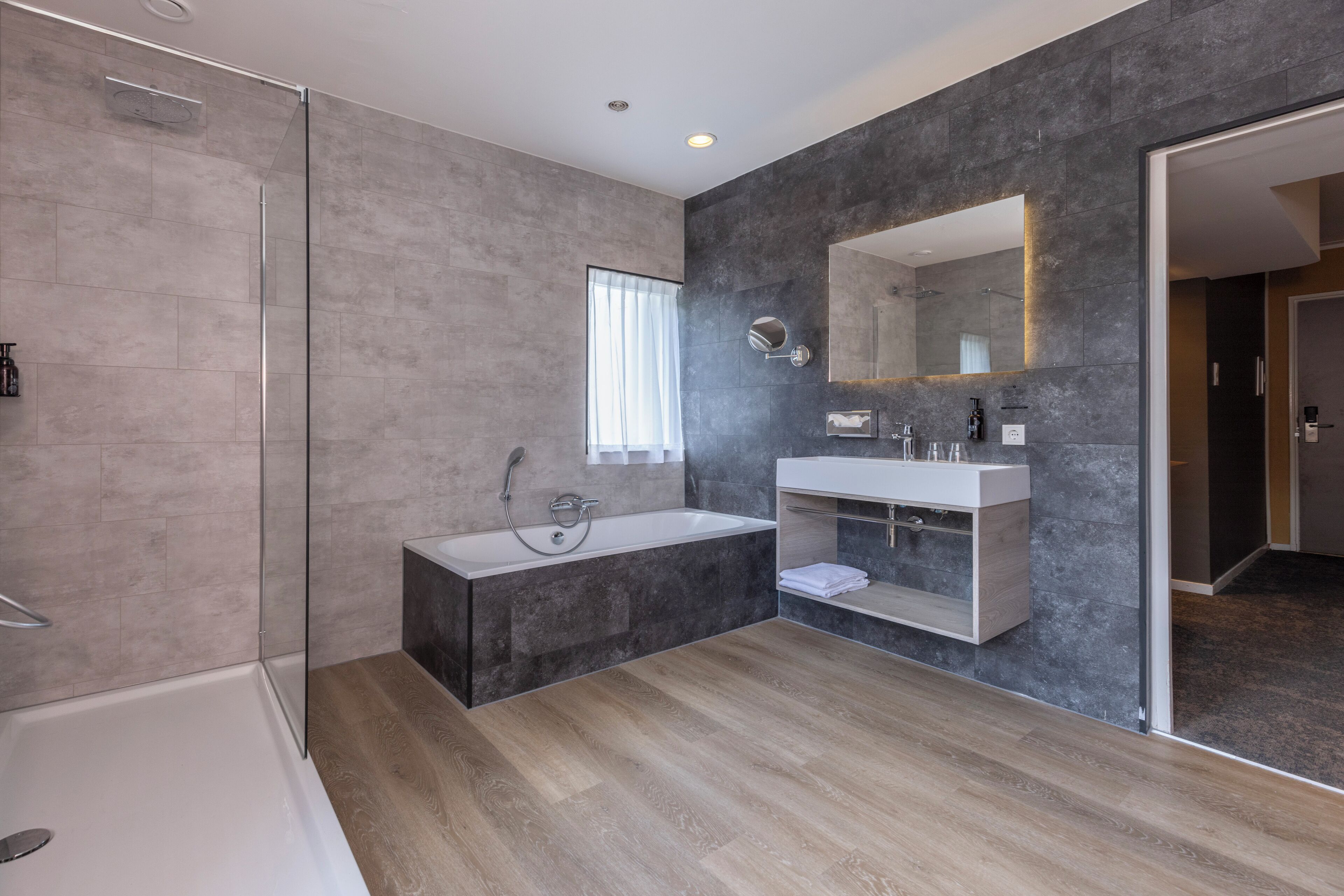 Un baño moderno con ducha de vidrio, bañera independiente y tocador con espejo.