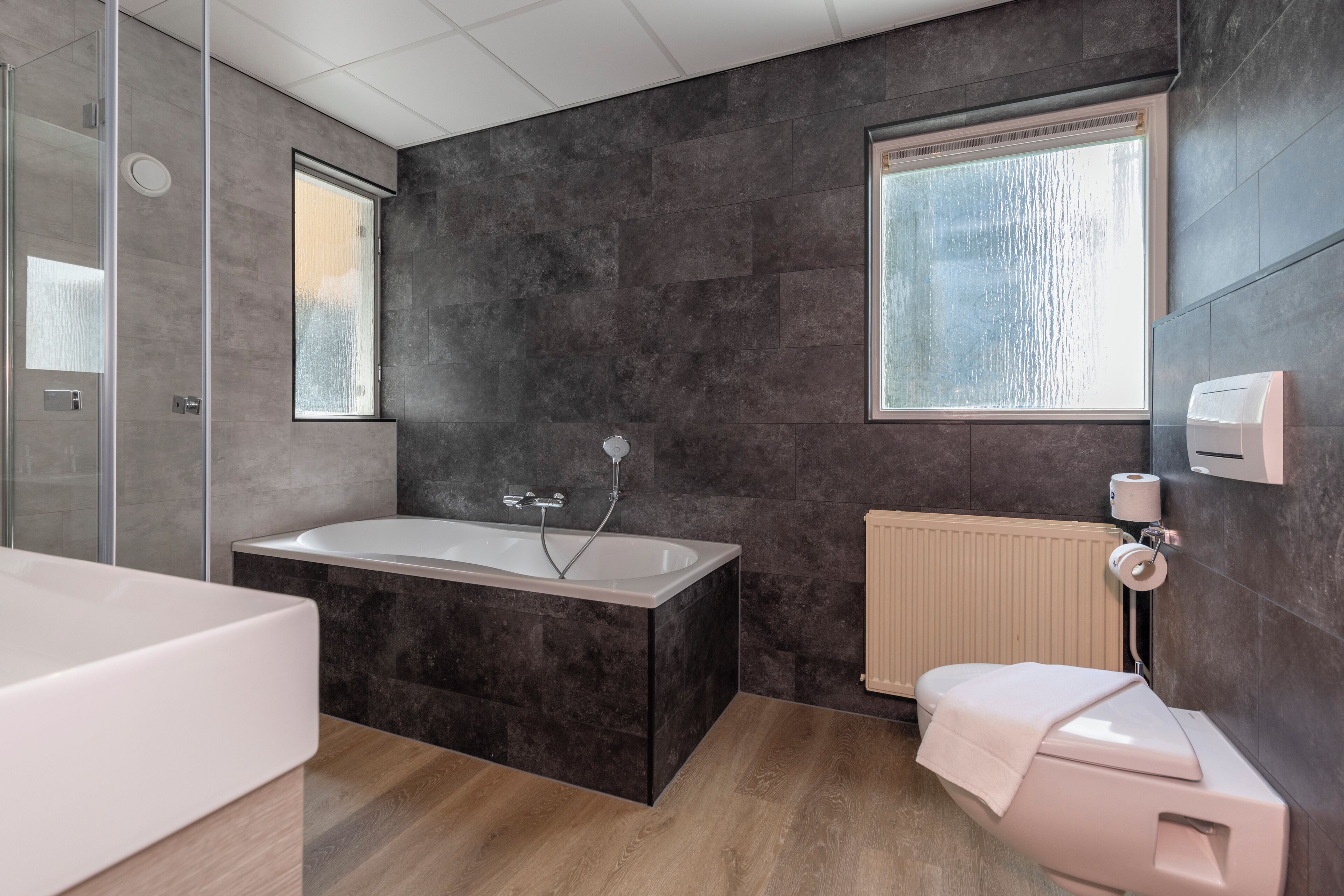A modern bathroom with a bathtub, a toilet, and a shower area.