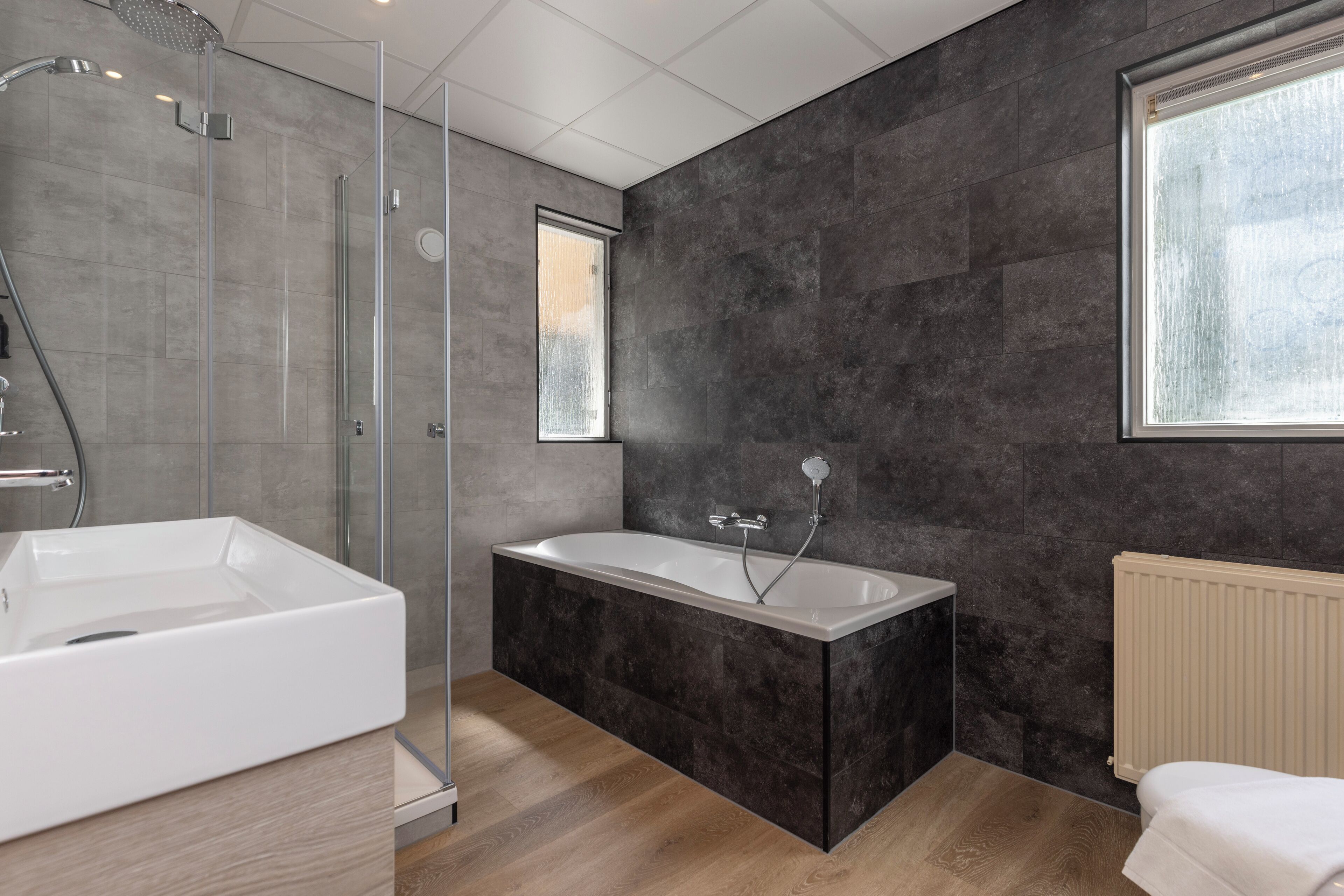 Un baño moderno con ducha de vidrio, bañera independiente y un amplio ventanal que proporciona luz natural.